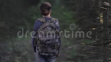 害怕的男孩走过一片可怕的干燥森林，在晚上缓慢地环顾四周