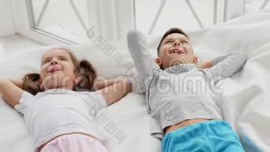 两个可爱的孩子躺在舒适的沙发上，双手捂着头，舌头伸出来，用<strong>胳膊</strong>肘打架。