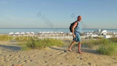 一个带着赤脚背包的人正在海边的背景下赤脚行走。