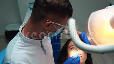戴着医用蓝色手套、口罩和眼镜的年轻牙医用牙镜`牙坝来治疗病人的牙齿