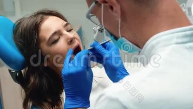 戴眼镜的年轻牙医，检查年轻的黑发女人`病人使用<strong>牙齿</strong>的<strong>问题</strong>