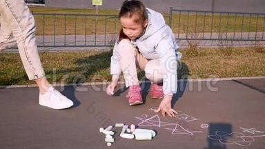 一家人在画画。 一个和母亲在一起的孩子正在沥青上用粉笔画画。