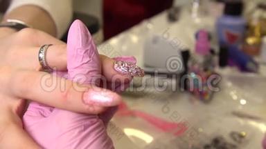 用美甲师把莱茵石贴在画好的指甲、化妆品和指甲上的宏景镜头，接近指甲