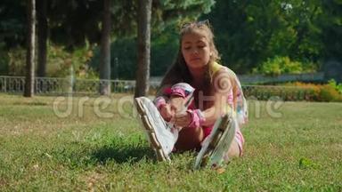 坐在草地上的小女孩穿上了她的<strong>旱冰鞋</strong>