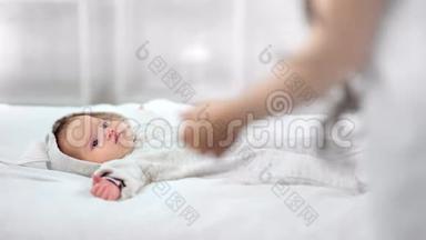 柔软的妈妈手牵着可爱的小宝宝在床上醒来，在白色的室内享受早晨