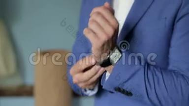 一个成功的人的特写是戴上手表。 男人手`手表