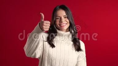 年轻的拉丁女人，完美的化妆，竖起大拇指，在红色上签名