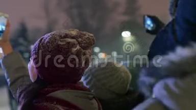 圣诞音乐会上的人群在舞台附近举起双手在智能手机摄像头上录制视频和自拍照片
