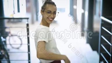年轻笑容可掬的美女戴着透明眼镜、白色t恤和红色长裙摆姿势的画像