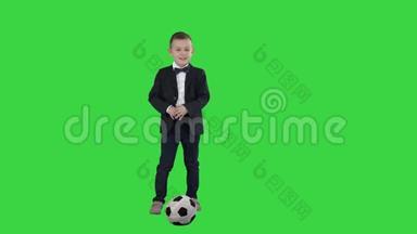 穿着正式西装的男孩在绿色屏幕上踢足球，铬钥匙。