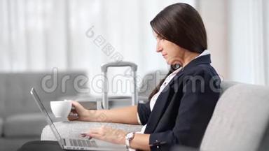 商务旅行时，女商务人士在笔记本电脑上喝茶，打字，中等特写