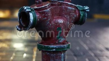 特写漏水消防栓，背景上有步行人群。 城市的旧红色消防栓