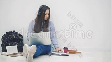 可爱的亚洲女孩坐在地板上，参与考试的准备过程。 周围都是学习用品..