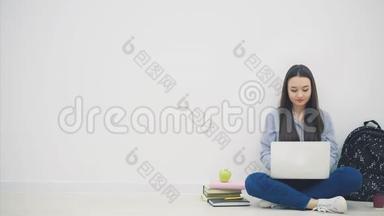 可爱的年轻亚洲女士坐在地板上，以洛托斯的姿势，在互联网上搜索，挥手问好。 学校用品