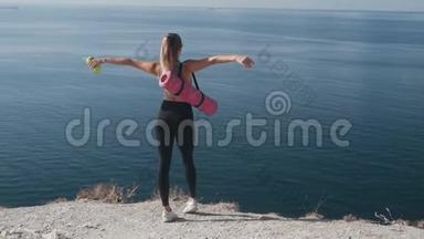 从侧面看，身穿运动服的女人站在悬崖边上，张开双臂