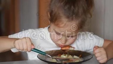 小女孩用勺子吃汤。 孩子吃美味的午餐。