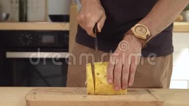 厨师在木板上切菠萝。 男人厨师手在厨房里切菠萝。 新鲜菠萝楔入木切割
