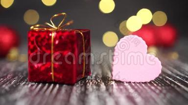 红色礼盒搭配金结和粉心特写.. 背景中鲜艳的装饰球.. 圣诞树<strong>灯闪烁</strong>