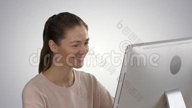 学生金发女孩看着电脑显示器，在渐背景上微笑。