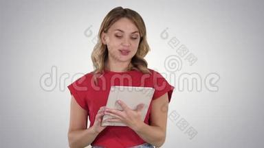 金发女人穿着红色的平板电脑，在渐变背景下阅读到相机上。