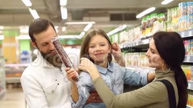 爸爸<strong>妈妈</strong>和女儿在商店买香肠，爸爸把女儿抱在<strong>怀里</strong>