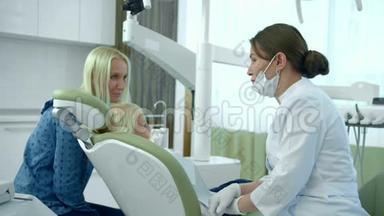 小<strong>女孩</strong>坐在牙科椅上，妈妈和医生说话