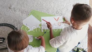 两个孩子在家一起用<strong>彩色铅笔画</strong>画