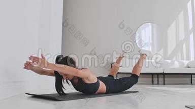 年轻有魅力的女人在双腿基克斯锻炼，灰色工作室。 年轻有魅力的女人练习瑜伽，伸展身体
