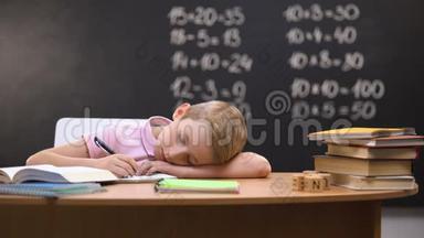 疲惫的小学生在桌子上打盹，在准备作业时睡着了
