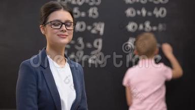 年轻的女教师寻找相机，学生解决数学练习，工作