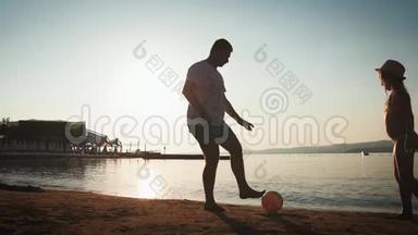 夏天<strong>一家人</strong>在海滩上踢足球。 父亲和<strong>女儿</strong>在户外踢足球。 友好的概念