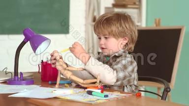 喜笑颜开的小学生在书桌前画画.. 9月1日 孩子在课堂上以黑板为背景学习