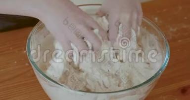 幼儿用手<strong>揉搓</strong>和混合面包面团放入玻璃搅拌碗中.. 当她做面团的时候，她的手特写
