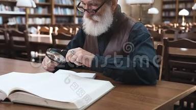 坐在图书馆里，用放大镜与书合作的戴着眼镜的长胡子<strong>老</strong>人的侧视图