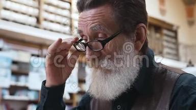 在图书馆看书的带眼镜的大胡子老人的侧视
