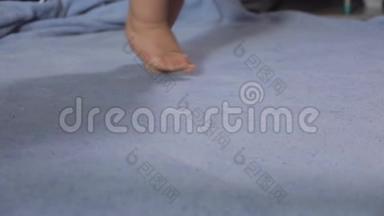 可爱的孩子们用蓝色的毯子脚趾头走路