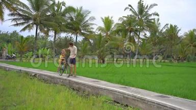 一个年轻人和他的小儿子骑着自行车穿过美丽的稻田。 前往<strong>东南亚</strong>构想