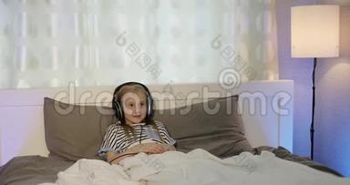 戴着耳机的<strong>小女孩</strong>和男孩躺在床上<strong>听音乐</strong>。
