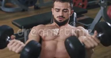 一个非常健康的年轻人正在健身房锻炼，在他的三头肌里，他是通过在健身房举重来锻炼的
