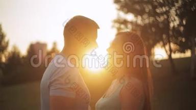 两个情人在公园日落时接吻的剪影。