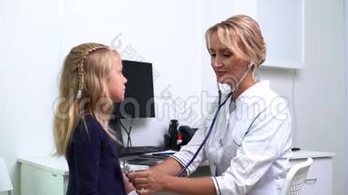 儿科医生用听诊器检查金发的年轻女孩