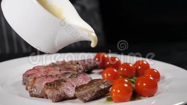 厨师在餐厅做饭。 厨师在烤肉片上撒上一些白酱，在白色盘子上配上樱桃番茄