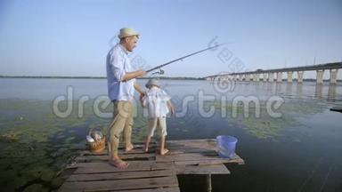 亲子关系，快乐爸爸在联合户外度假期间教小儿子在河岸钓鱼