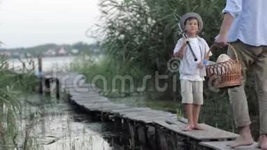 暑假，带着钓竿的小男孩和爸爸一起到<strong>芦苇丛</strong>中去钓鱼，还有一个小篮子在家里钓鱼