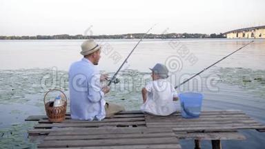 无忧无虑的童年，幸福的家庭，小男孩和男人，懒洋洋地坐在河边的码头上钓鱼