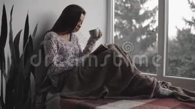 <strong>漂亮</strong>的年轻女士正坐在窗台上看书，在房子里喝茶。 <strong>大</strong>窗户，<strong>绿</strong>植..