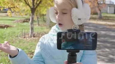 快乐可爱的小vlogger在公园长椅上制作在线视频录制vlog。 记录vlog和博客概念