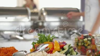 一个带盘子的女人把食物放在自助餐上，在酒店餐厅自助服务，在盘子里装满各种食物