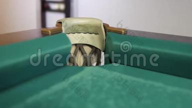 在绿色的台球桌上，球打在口袋里。 台球桌上破旧的布。