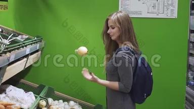 可爱的小女孩在超市选择蔬菜。 穿灰色连衣裙的快乐女孩在购物时摆弄蔬菜。